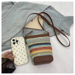 Détail d'un sac bandoulière en paille colorée avec garniture et sangle en cuir synthétique