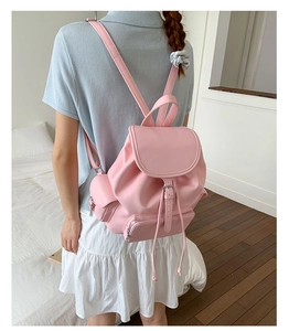 Rear view of model wearing a soft pink faux leather backpack with buckle flap and side pockets