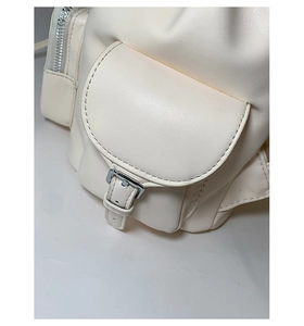 Detailed macro view of off-white leather backpack featuring silver buckle and zipper