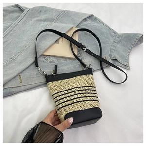 Detail of raffia woven crossbody bag with black stripes and adjustable leather strap