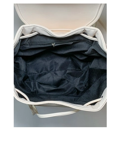 Detailed top view of the spacious cream backpack interior with black lining and zipper pocket
