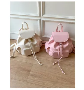 Detail of soft PU leather backpacks in beige and pink with drawstring and flap closure