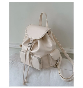 Macro detail of creamy white PU leather backpack showing drawstring and decorative buckle