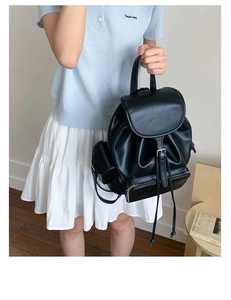 Detail of minimalist black faux leather backpack with drawstring closure and front zipper pocket