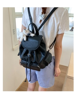 Classic black leather drawstring backpack with cute plush bear pendant shown on a model