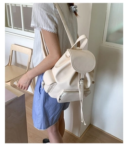 Side view of model wearing a cream vintage PU leather backpack with buckle detail