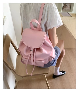 Pink glossy PU leather backpack with metal buckle closure shown in a lifestyle indoor setting