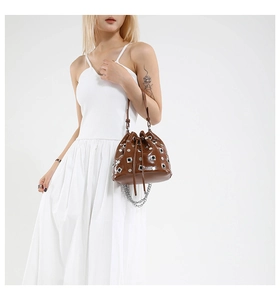 Detail of brown leather bucket bag with silver rivet studs and drawstring closure