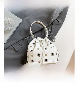 Detail shot of a white bucket bag with silver studs and chain strap on a blazer