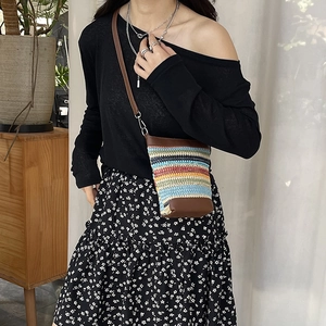 Sac bandoulière en paille rayé arc-en-ciel avec garniture en cuir porté par un mannequin