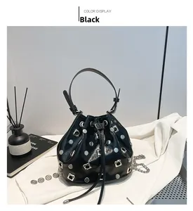 Detail of black rivet bucket bag with silver studs and chain strap on white fabric