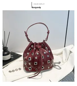 Close-up of wine red bucket bag featuring silver rivet studs and chain strap detail