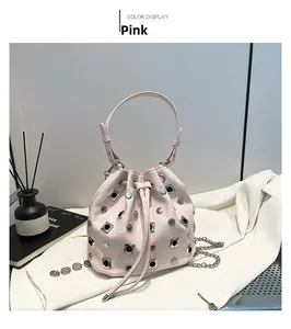 Detail view of pink bucket bag with silver studs and chain strap on soft fabric