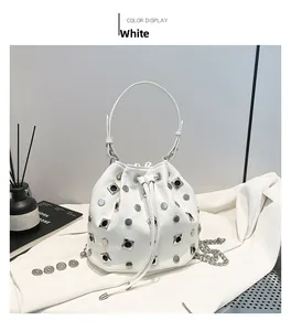 Detail of white bucket bag featuring silver rivets, drawstring closure and chain strap