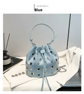 Detail of light blue bucket bag with silver studs and chain strap on lifestyle background