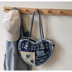 Detailed close-up of heart-shaped denim shoulder bag with Y2K star patchwork and frayed edges