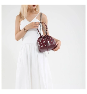 Close-up of wine red bucket bag featuring silver rivets and metal chain strap details