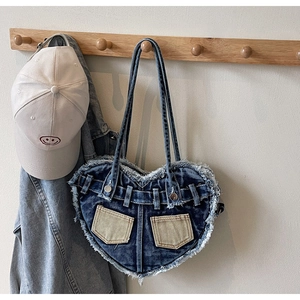Close-up of heart-shaped washed denim shoulder bag with frayed edges and retro details