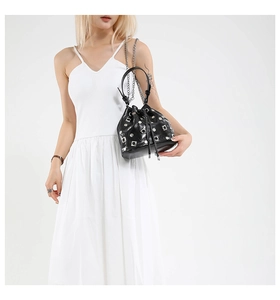 Detail of black drawstring bucket bag with silver studs and chain strap on a model