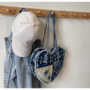 Detail of heart-shaped denim patchwork handbag with distressed edges and star pocket
