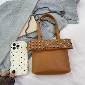Brown punk rivet chain bag with bow design over denim jacket background for women