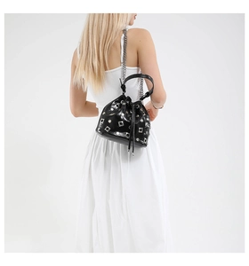Back view of a black studded bucket bag with silver chain strap shown on a model