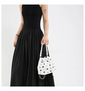 Detailed view of white bucket bag featuring silver rivets and drawstring closure