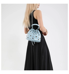 Detailed back view of a light blue bucket bag with silver studs and chain strap
