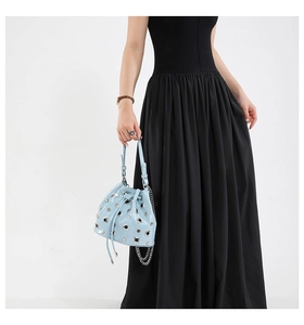 Detail of light blue punk bucket bag with silver studs and chain strap on black dress