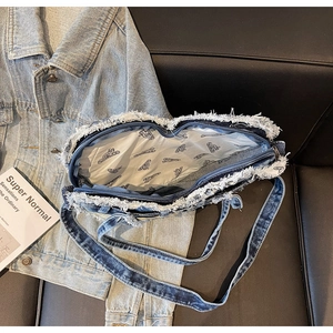 Detail of washed denim shoulder bag showing frayed edges and patterned lining fabric