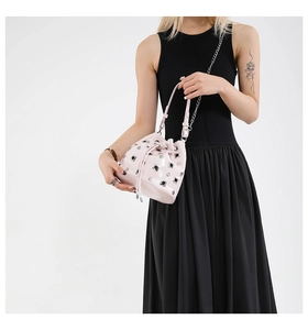 Detail of light pink bucket bag with silver studs and chain strap on a model