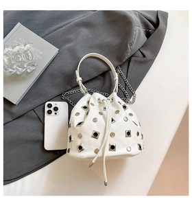 Detailed close-up of white leather bucket bag with silver studs and metal chain strap
