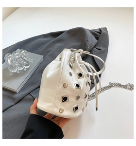 Detail of white bucket bag with silver studs, metallic chain strap and drawstring closure