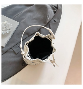 Detailed close-up of white bucket bag featuring silver grommets and black lining