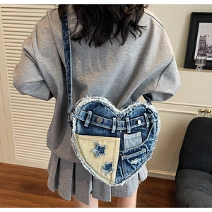 Detail of heart-shaped denim shoulder bag with frayed edges and star patchwork design