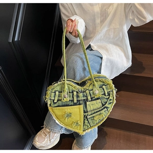 Detailed view of heart-shaped washed denim handbag with fringe edges and star patterns