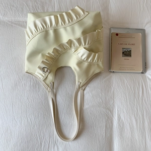 Detailed view of cream nylon bucket bag featuring triple-layered ruffle trim and silver D-ring