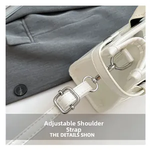 Detail view of white leather handbag with adjustable strap and silver metal hardware accents