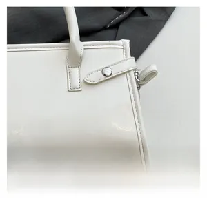 Detailed close-up showing white glossy leather texture and silver buckle of the handbag