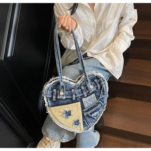 Detailed close-up of heart-shaped denim patchwork bag with raw edges and star design