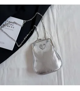 Detail of silver metallic PU bag featuring pearl heart inlay and retro clasp closure