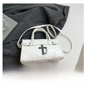 Detailed view of a white crossbody bag with vintage metal cross and phone for size reference