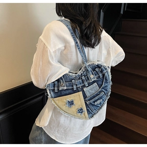 Detail of heart-shaped denim shoulder bag with raw edges and metal hardware detail