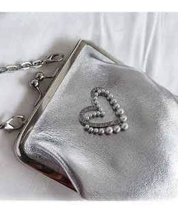 Detail of silver PU bag with pearl heart embellishment and rhinestone accents