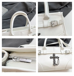 Detail view of white leather tote showing metal zipper and silver cross pendant ornament