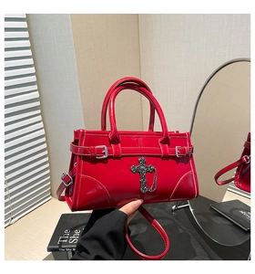 Close-up of red patent leather Boston bag with vintage silver cross metal decoration