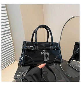 Detail of glossy black leather crossbody bag featuring silver gothic cross and chain