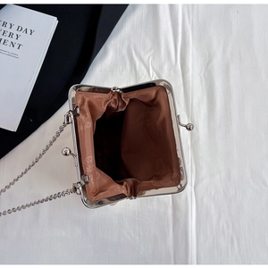 Top view of mini shell bag showing kiss-lock closure, silver chain, and patterned lining