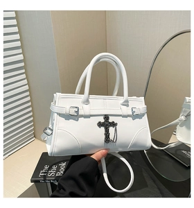 Close-up of white gothic bag with large vintage black metal cross and chain detail