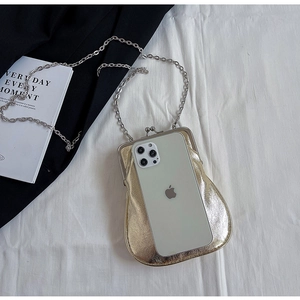 Macro shot of gold metallic clutch bag size comparison with a white smartphone